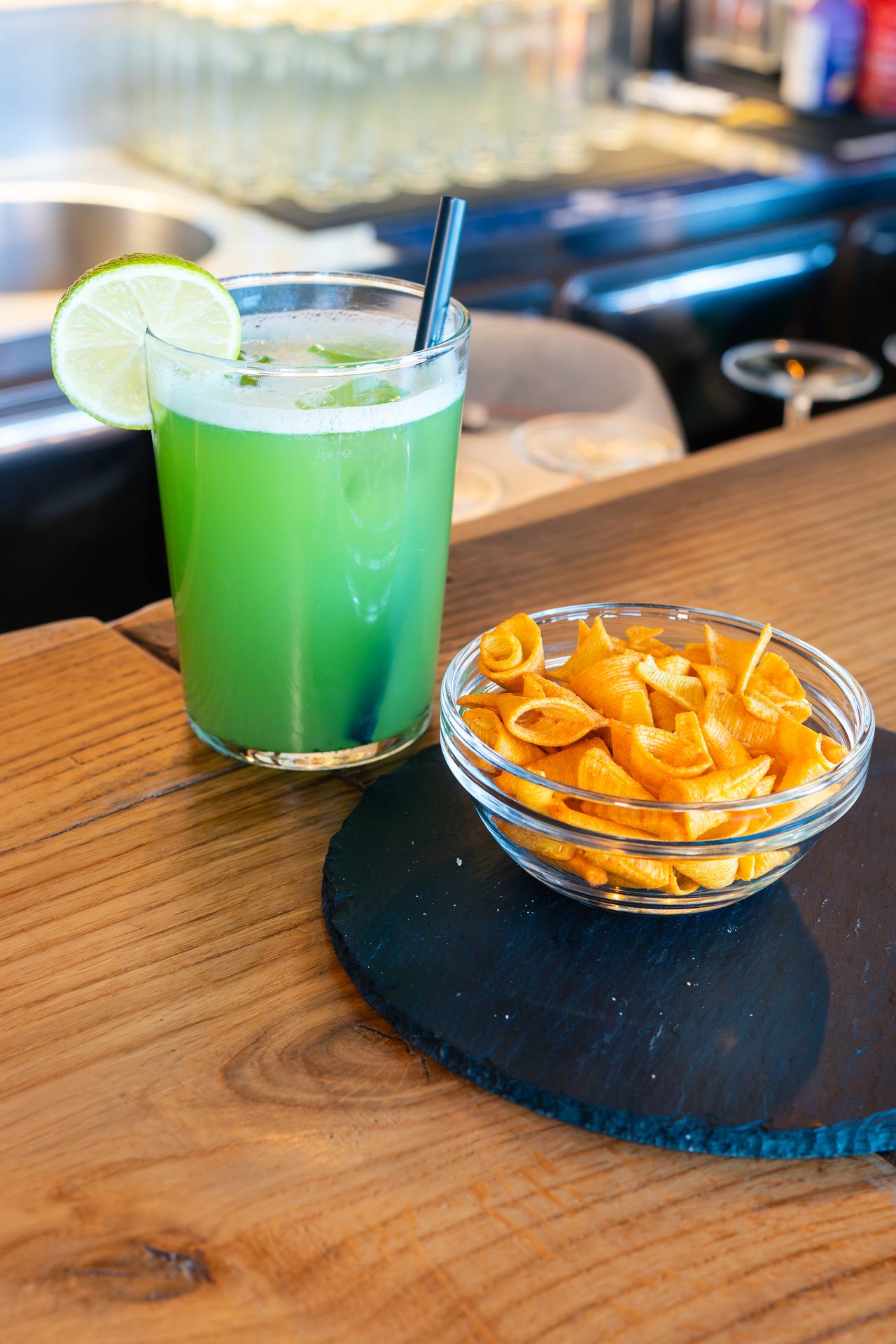 Cocktail verde con lime e snack serviti sul bancone in legno di Borgo 22